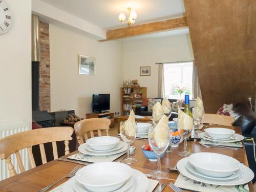 a dining room with a table with plates and wine glasses at The Stable in Foxham