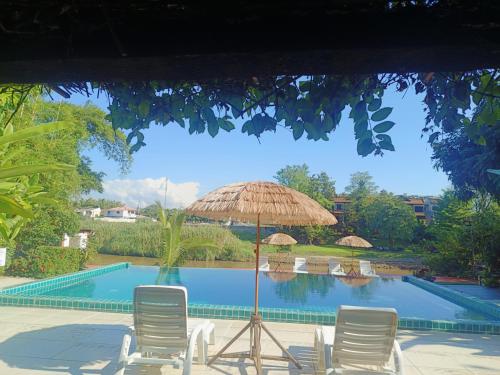 a patio with chairs and an umbrella and a pool at Tonnam Homestay in Chiang Mai