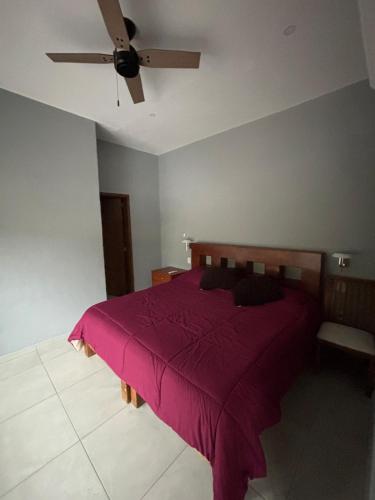 a bedroom with a purple bed with a ceiling fan at C apartment in Ajijic
