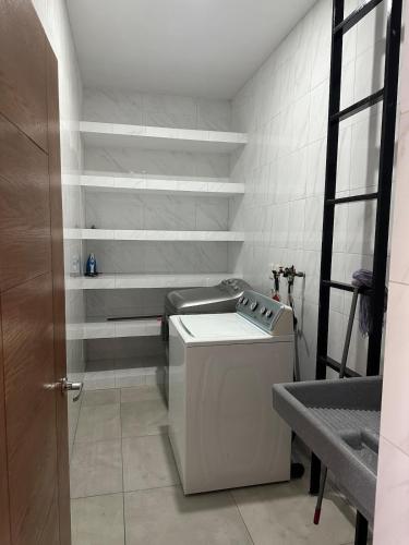 a washing machine in a bathroom with white shelves at C apartment in Ajijic