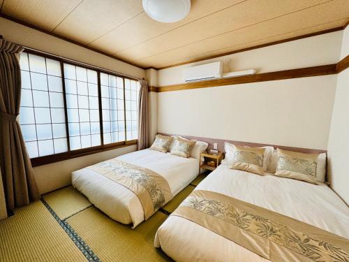 two beds in a room with two windows at Private Room near Iriya in Tokyo