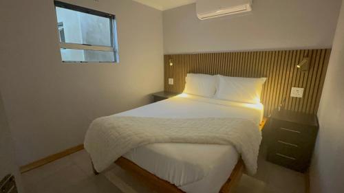 a bedroom with a bed with white sheets and a window at Siyaya Palace in Jozini