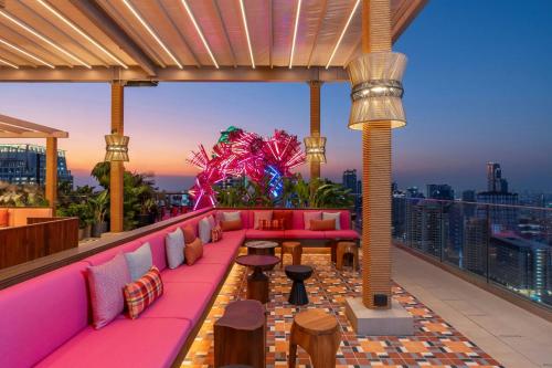a rooftop bar with pink furniture and a view of the city at Moxy Bangkok Ratchaprasong in Bangkok
