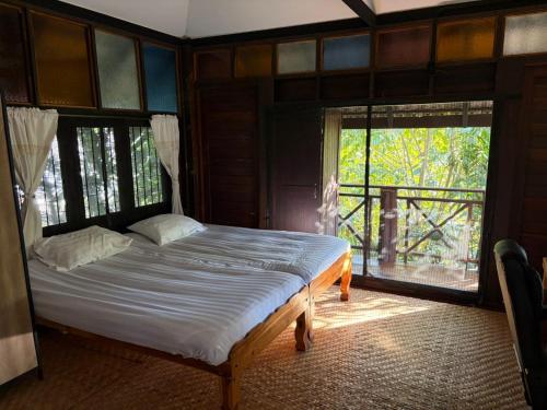 a bedroom with a bed and a large window at The Bodhi House in Chiang Mai