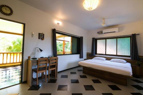 a bedroom with a bed and a desk and windows at Saguna Baug Agro Tourism in Neral