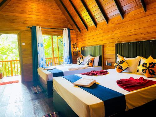 two beds in a room with wooden walls at Sigiriya Carpenter Cottage in Sigiriya