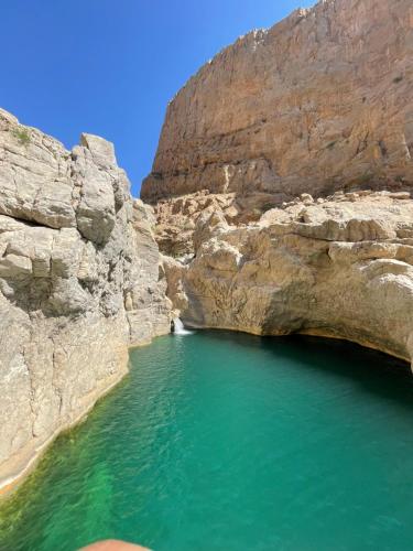 a pool of emerald green water in a canyon at Wadi hawer tour guiding and local farm tour in Biḑ‘ah