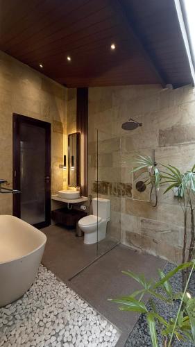 a bathroom with a tub and a toilet and a sink at Eden Villas Lombok in Kuta Lombok