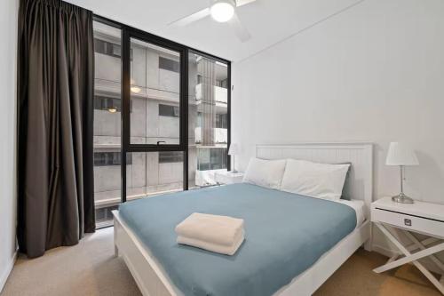 a bedroom with a blue bed and a large window at Level 10 Views 2BR with Private Balcony & Parking in Brisbane