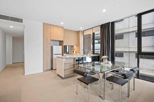 a kitchen with a glass table and black chairs at Level 10 Views 2BR with Private Balcony & Parking in Brisbane