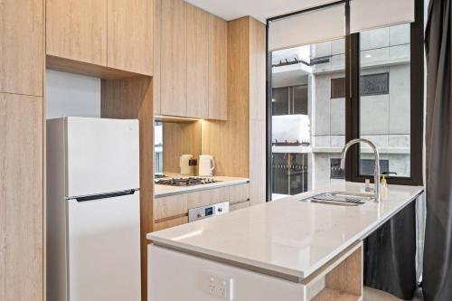 a kitchen with a white refrigerator and wooden cabinets at Level 10 Views 2BR with Private Balcony & Parking in Brisbane