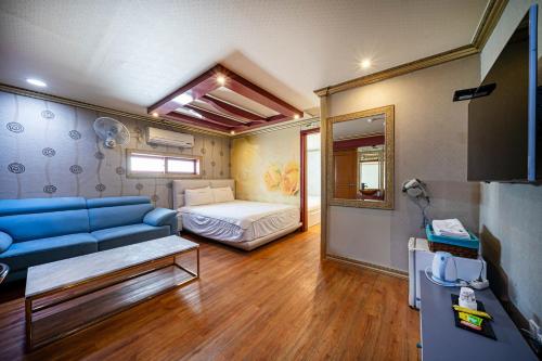 a living room with a blue couch and a bed at 센스모텔 in Sasang-yŏk