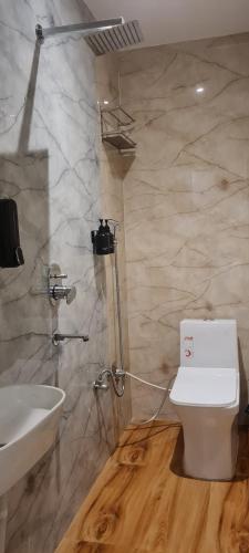 a bathroom with a white toilet and a sink at AmarVandana Palace in Rādha Kund