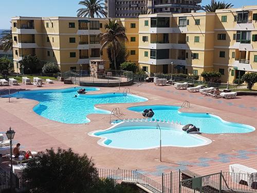 una gran piscina con 2 piscinas frente a algunos edificios en Apartamento Pepe, en Playa del Inglés