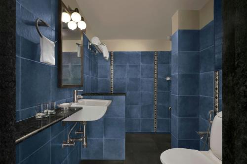 a blue tiled bathroom with a sink and a toilet at The Fern Samali Resort Dapoli, Series by Marriott in Dapoli