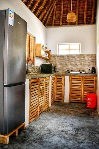 a kitchen with a stainless steel refrigerator and wooden cabinets at Amani Beach House, Ushongo in Pangani