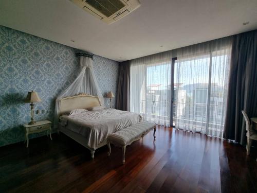 a bedroom with a canopy bed and large windows at Luxury Villa with Panoramic Seaview, Private Pool in Ban Saiyuan (1)