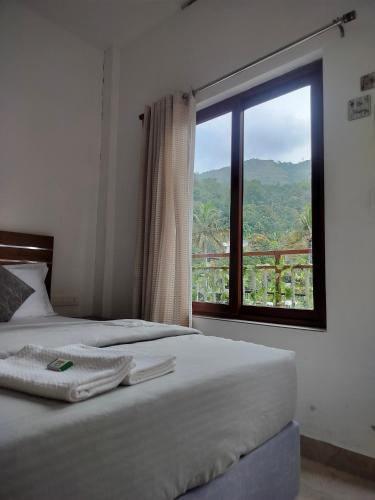 a bedroom with two beds and a large window at Asprin Homestay in Munnar