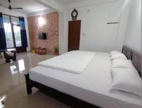 a bedroom with a large white bed with a clock on the wall at Tapovan Fruitopia in Sultan Bathery