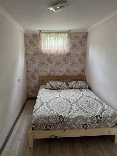 un dormitorio con una cama con edredón y una ventana en Home, en Dilijan