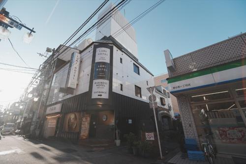 a building with a clock on the side of a street at Lumi Hotel Tokyo Shinkoiwa JR新小岩駅南口 徒歩1分 in Tokyo