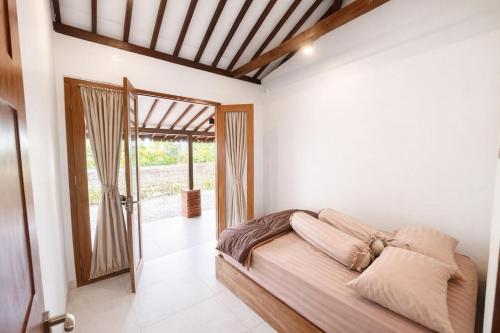 a bedroom with a bed in a room with a door at Lonovilla Menoreh Yogyakarta in Junggrangan