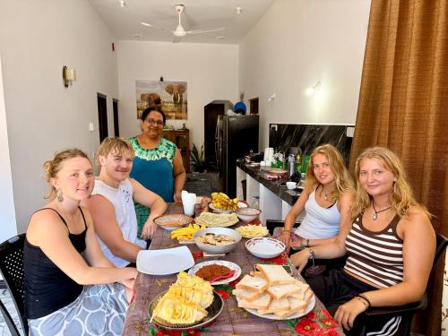 a group of people sitting around a table with food at Midigama Lucky Villa in Midigama East