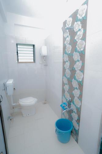 a bathroom with a toilet and a flower shower curtain at Aashray Guestroom in Murud