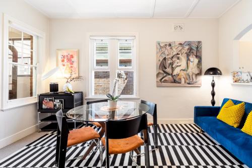 a living room with a glass table and a blue couch at Ocean-View Art Stay & Private Rooftop, Walk to Circular Quay in Sydney