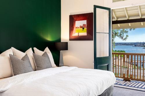 a bedroom with a white bed with a green wall at Ocean-View Art Stay & Private Rooftop, Walk to Circular Quay in Sydney