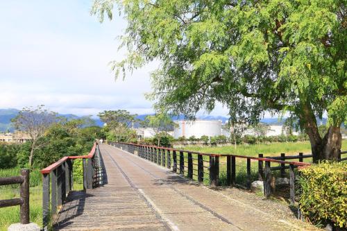 un puente de madera sobre un campo con un árbol en Huadong Homestay, en Taitung