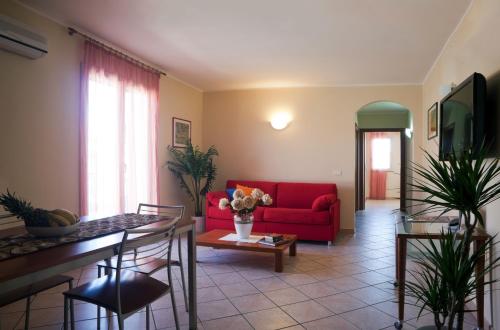 sala de estar con sofá rojo y mesa en Motta Residence Hotel en Motta SantʼAnastasia