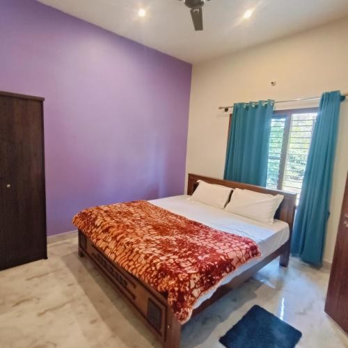 a bedroom with a bed with purple walls and a window at Golden Valley Abode in Siddapur