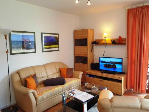 a living room with a couch and a flat screen tv at Fewo 1 im Fischerhaus mit Wintergarten und Terrasse in Seedorf