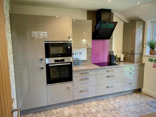 a kitchen with white cabinets and a stove at Station View in Pickering