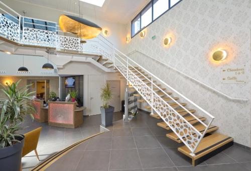 a spiral staircase in a lobby with plants at The Originals Boutique, Hôtel Le Lion d'Or, Fougères Ouest in Maen Roch