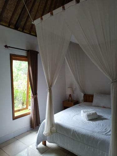 a bedroom with a canopy bed with a window at The Bukit Artha in Sidemen