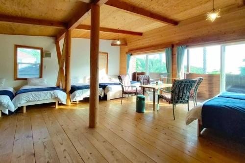 a bedroom with two beds and a table and chairs at プールサイドヴィラ館山 in Tateyama
