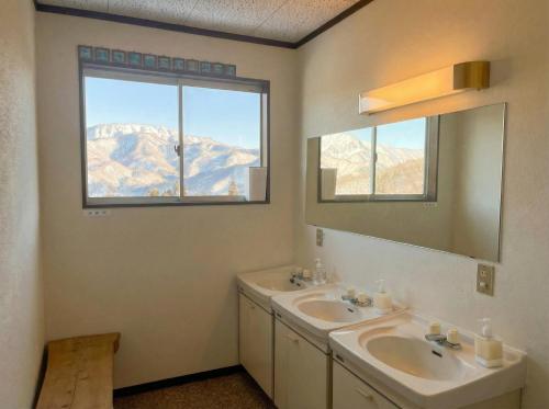a bathroom with two sinks and a mirror at Kamoshika Lodge Hakuba in Minami Otari