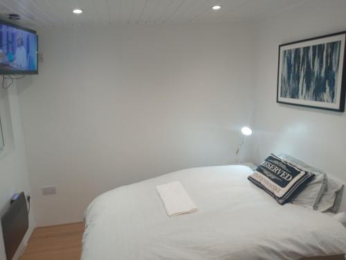 a white bed in a room with a tv at Lovely Timber Lodge Ensuite room in Corby Town centre NN17 in Rockingham