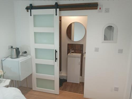 a bathroom with a white door and a mirror at Lovely Timber Lodge Ensuite room in Corby Town centre NN17 in Rockingham