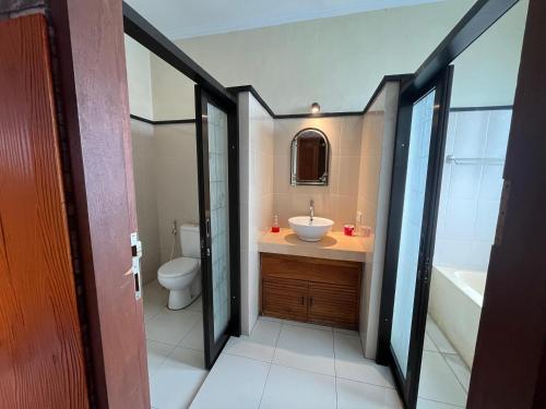 a bathroom with a sink and a toilet and a tub at Puji Bisma Ubud in Ubud