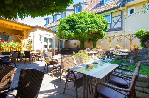 un patio al aire libre con mesas, sillas y un árbol en Hotel & Restaurant Ernst, en Giesen