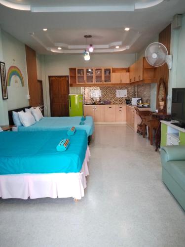 a bedroom with two blue beds and a kitchen at บ้านพัก สายรุ้ง in Ban Hua Saphan