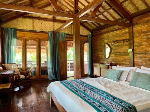 a bedroom with a bed in a room with wooden walls at Secret Beach Beachfront Villa in Papak