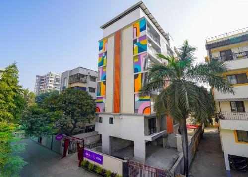a colorful building with a palm tree in front of it at Olive Hotel Wakad by Embassy Group in Pune