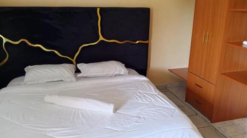 a bed with white pillows and a black headboard at palm ridge apartment Diani beach in Diani Beach