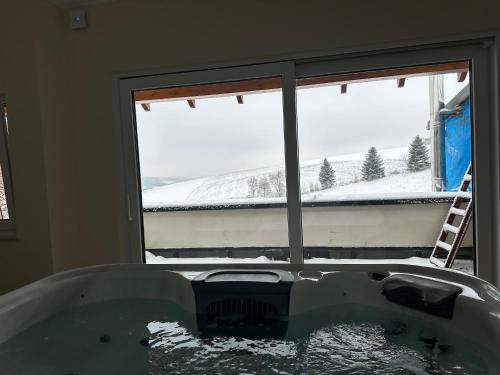 a bath tub in front of a window with snow outside at Ferienwohnung Weitblick mit Whirlpool in Lasel