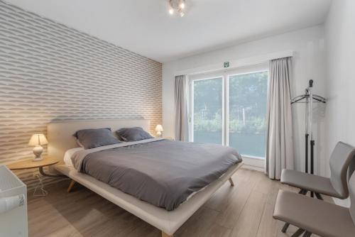 a bedroom with a bed and a large window at Parkhouse C0 in De Haan