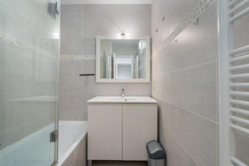a white bathroom with a sink and a mirror at Parkhouse C0 in De Haan